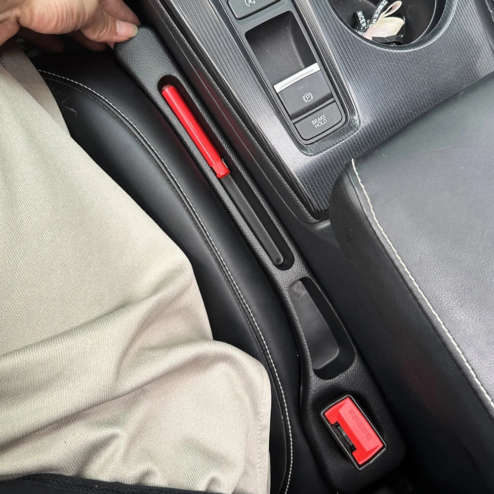 Black car seat gap filler placed between the seat and center console, shown in use with a hand