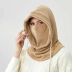 Person wearing a tan fleece winter hood with drawstrings and a face covering, shown from the front