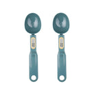 Two teal digital measuring spoons with small LCD screens on the handles, shown side by side