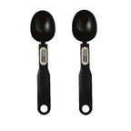Two black digital measuring spoon scales with small display screens, shown side by side on white background