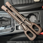 Pair of brown car seat gap fillers placed on a black car console between the seats and cup holders