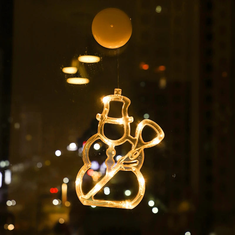 Warm white LED snowman ornament hanging on a window at night with city lights in the background