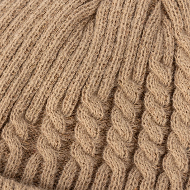 Close-up of a tan cable knit beanie showing detailed ribbed and twisted knit pattern