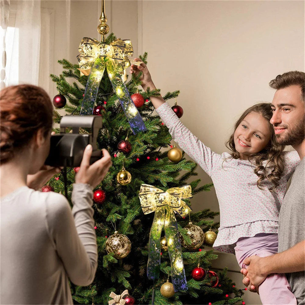 Gold ribbon string lights glowing on a Christmas tree, with a family decorating and taking photos