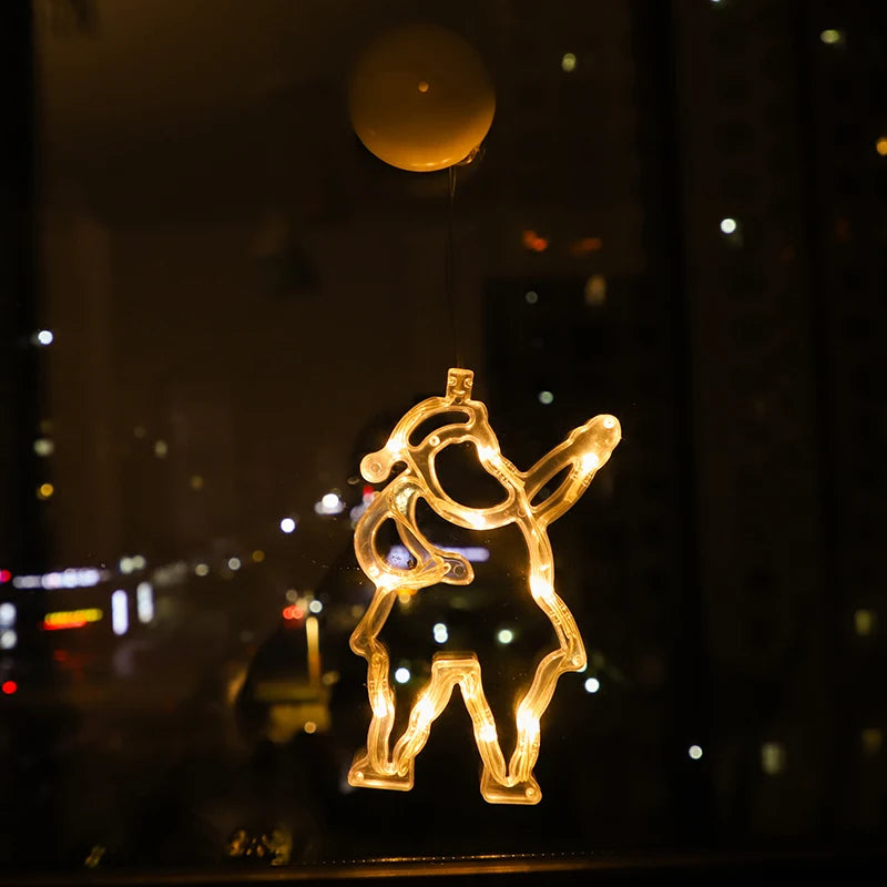 Warm white LED Christmas ornament shaped like a dancing figure, hanging on a window at night