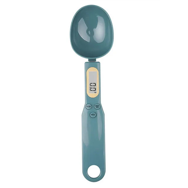 Teal digital measuring spoon scale with LCD screen and buttons, shown from above on a white background