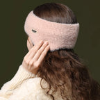 Soft light pink fuzzy ear warmer headband worn on a woman with long brown hair, rear view