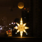 Warm white LED star-shaped ornament hanging on a window with city lights blurred in the background