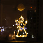 Warm white LED angel ornament hanging in a window at night with city lights in the background