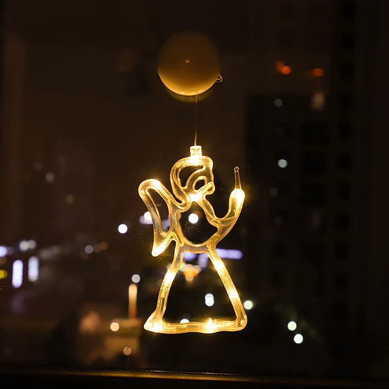 Warm white LED angel ornament hanging in a window at night with city lights in the background
