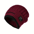 Cable knit beanie in dark red with black brim and patch detail, shown on a white background