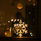 Transparent LED snowflake ornament glowing warm white, hanging on a window at night