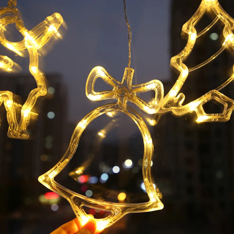 Warm white hanging LED Christmas ornaments shaped like a bell, reindeer, and tree, lit at night