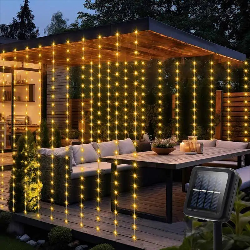 Warm yellow solar curtain string lights hanging from a patio roof, glowing at night over outdoor seating