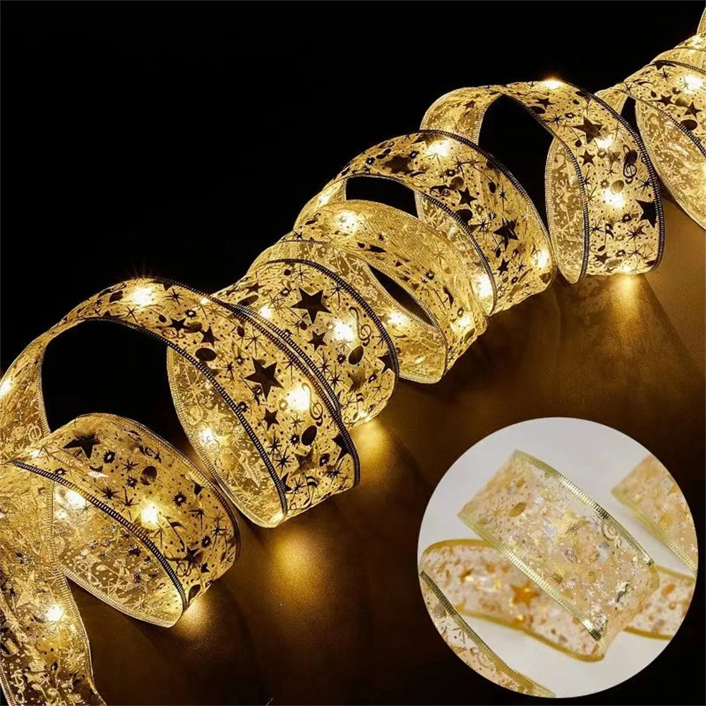 Gold ribbon string lights with star and snowflake patterns, glowing on a dark surface, close-up view