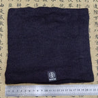 Black knitted neck warmer laid flat on a surface with a ruler for scale, tag showing "WINTER
