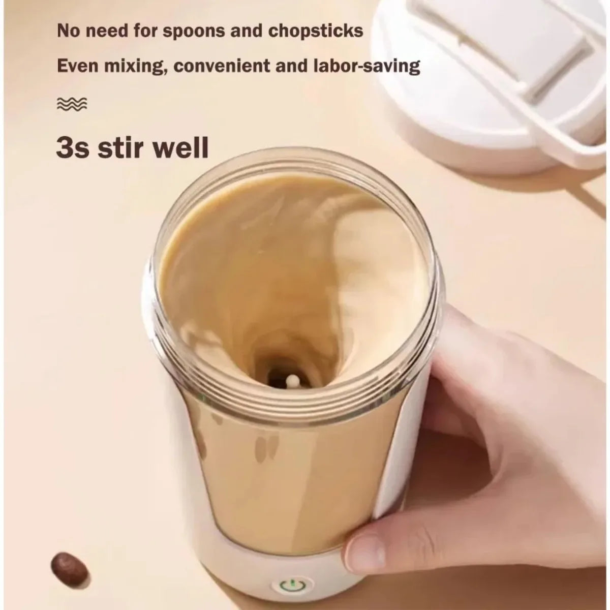 Hand holding a clear electric shaker cup with light brown liquid swirling inside, lid on the table