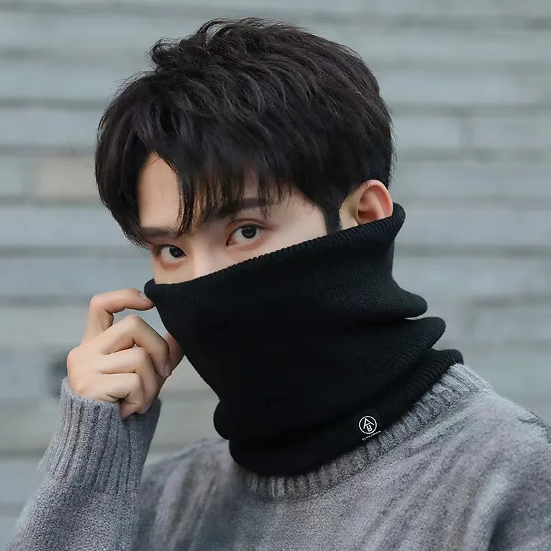 Black knitted neck warmer worn by a person in a grey sweater, covering neck and lower face