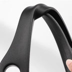 Flexible black car seat gap filler close-up, textured surface, held and bent by a hand