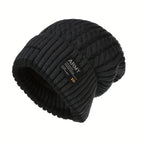 Thick black cable knit beanie with a ribbed cuff and a small patch on the front, shown on white