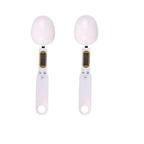 Two white digital measuring spoon scales with LCD screens and buttons, shown side by side on white background