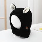 Black knitted dog ear muffs with white inner ears on display, featuring a small brown dog patch