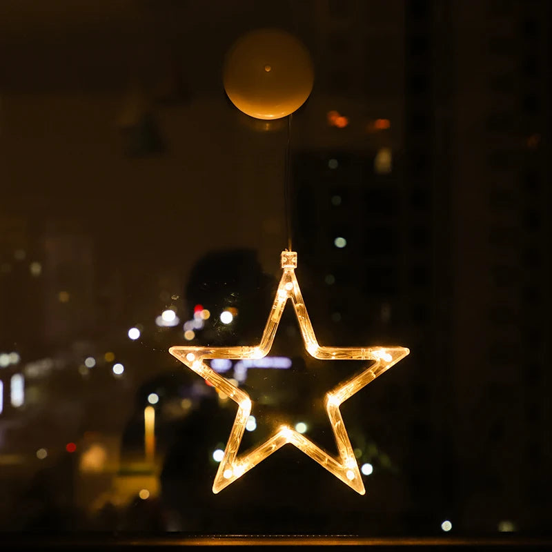 Star-shaped warm white LED ornament hanging on a window, glowing at night with city lights behind