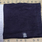 Black knitted neck warmer laid flat with a measuring ruler beside it, tag labeled "WINTER" visible