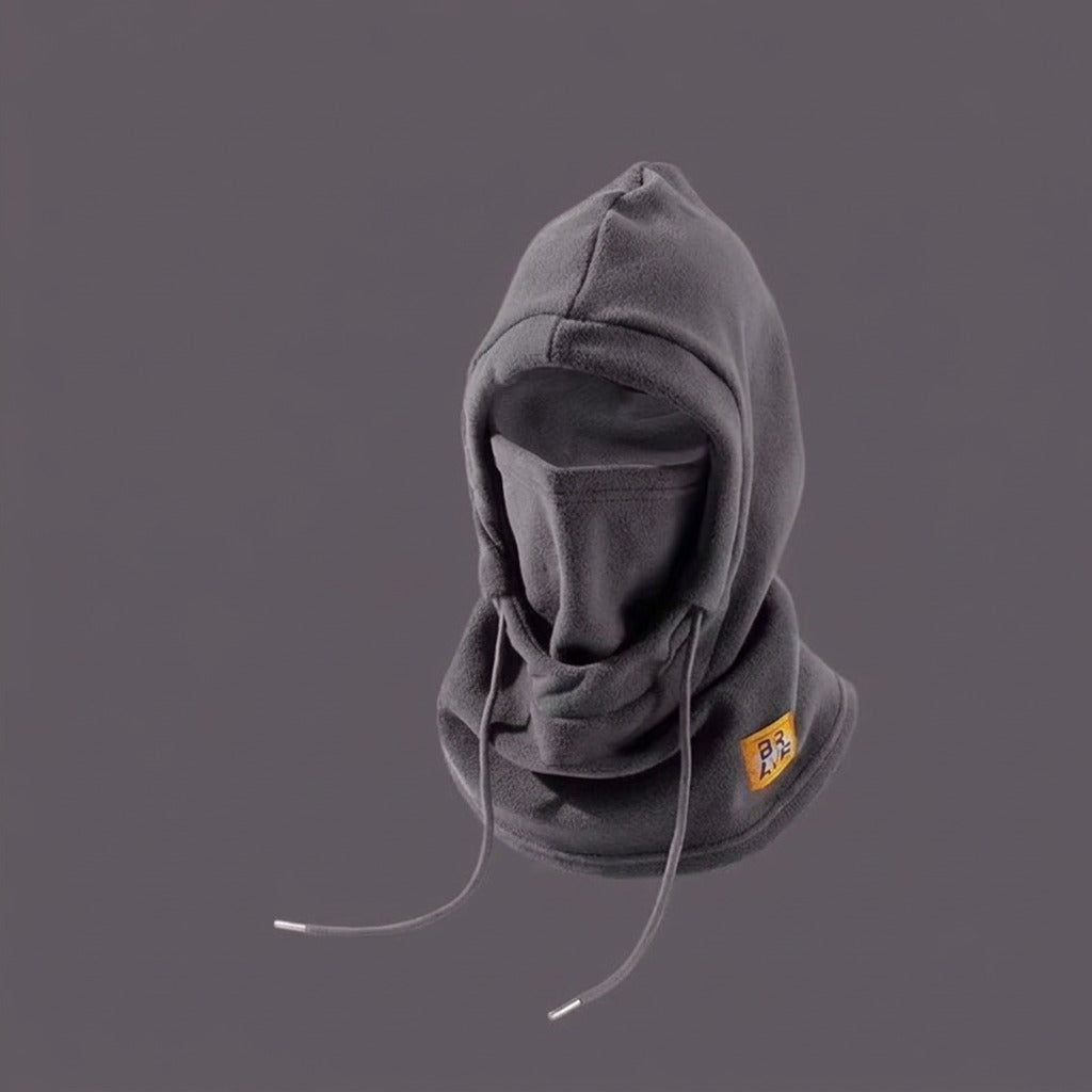 Dark grey fleece winter hood with built-in face covering, drawstrings, and a small yellow patch