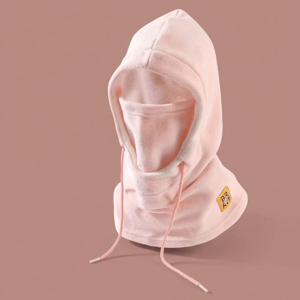 Pale pink fleece winter hood with drawstrings and a patch, displayed on a plain mauve background