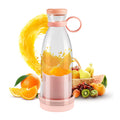 Clear and pink portable blender bottle with orange slices inside, fruit basket and juice splash behind